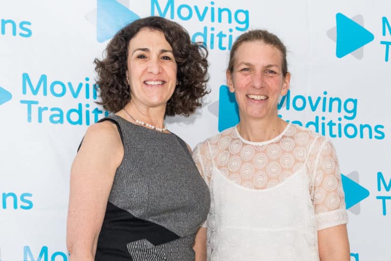 Deborah Meyer and Sally Gottesman standing in front of a backdrop of Moving Traditions logos